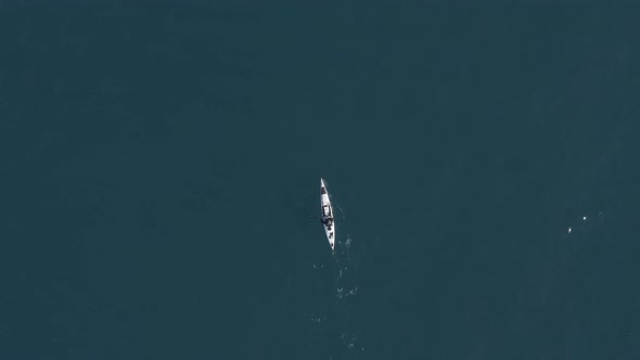 Single seat fishing canoe rowing at calm open sea water, Aerial view.