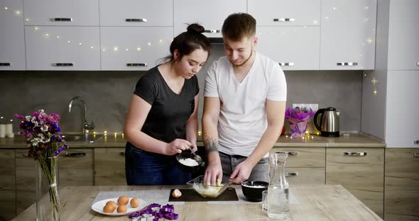 Young Couple Guy and Girl in Quarantine Cook at Home in the Kitchen Together Spend Time Kissing 