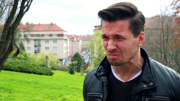 Young Handsome Man Stands, Is Angry and Yells in Park