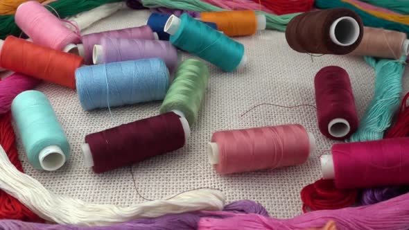 Falling multicolored spools on burlap against the background of colorful mouline threads