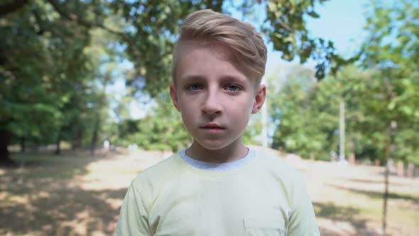 Shocked Caucasian Boy Feeling Overwhelmed Standing in Park, Emotions Concept