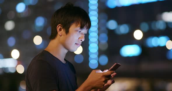 Man use of mobile phone in city at night