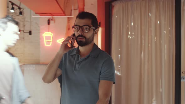 Middle Eastern Man Talking on Phone and Going in Coworking