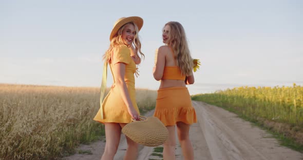Two Cute Blondes are Walking in the Field
