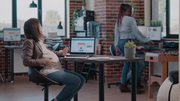 Pregnant Employee Working on Business Project with Laptop