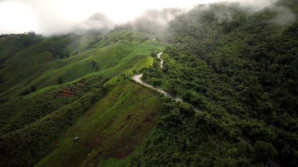 Aerial view flying above lush green tropical rain forest mountain with rain cloud cover during the r