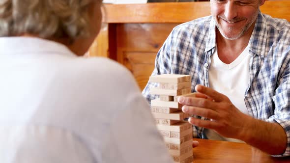 Senior friends playing jenga game on table 4k