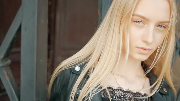 fashion portrait of a beautiful young woman with blue eyes and blonde hair in a leather jacket outdo