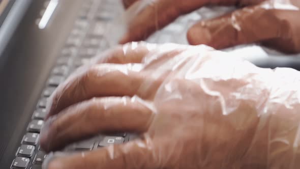 Remote work at home. Hands in antibacterial gloves are typing on a laptop keyboard