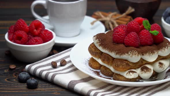 Portion of Classic Tiramisu Dessert with Raspberries and Blueberries, Savoiardi and Cup of Coffee