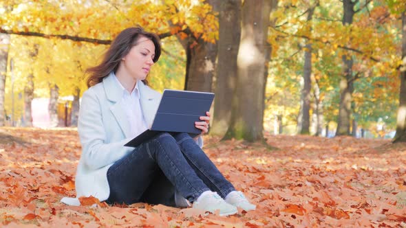 Woman Working with Laptop Sitting on the Ground in Park