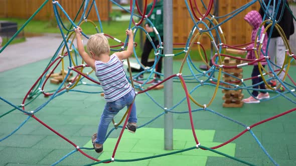 Life of Children in a Modern City - Little Boy Is Having Fun on the Playground Near the House