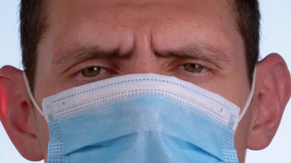 Young Man in a Medical Protective Face Mask Looking at the Camera on the Street Background