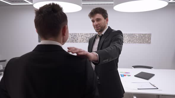 Positive Handsome Man Tapping Shoulder of Colleague Endorsing Coworker in Office Indoors