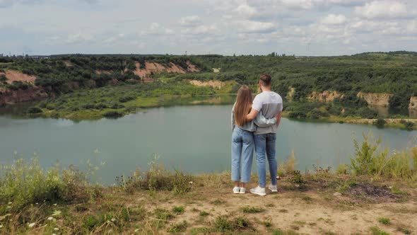 Couple Is Standing on a Mountain Cliff By the Lake. Couple in Love Hugging Against the Background