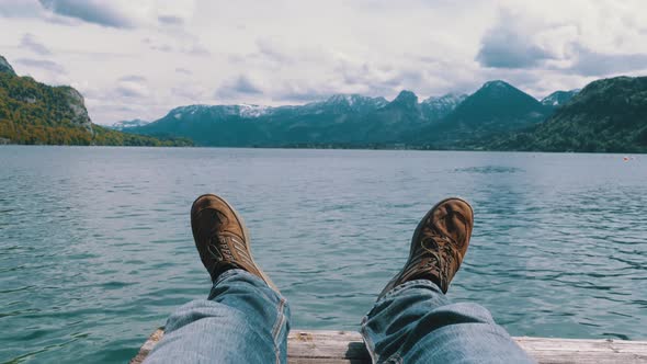 Human Feets on the Background of a Mountain Lake and Snow covered Mountains