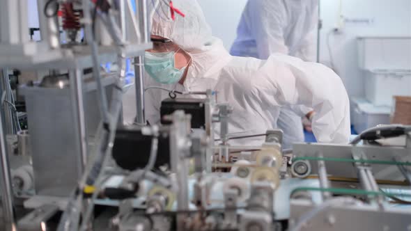 One factory worker close up check line of mask producing machine during it's working