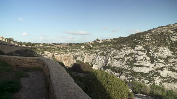 Canyon near Blue Grotto with Steep Hills and Greenery Growing on Slopes of Mountain