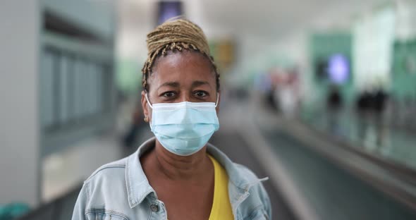 Mature african woman looking on camera while wearing safety face mask for coronavirus outbreak