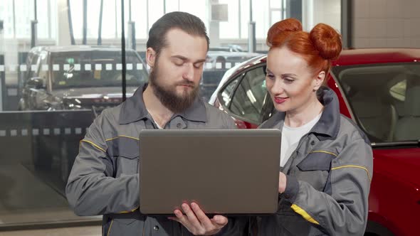 Bearded Car Mechanic Using Laptop at the Garage, Working with Female Colleague