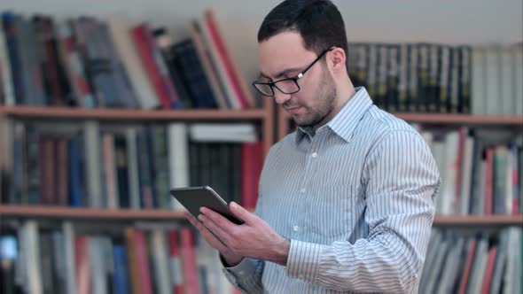 Young Male Teacher Hand Holding and Using Tablet in Classroom