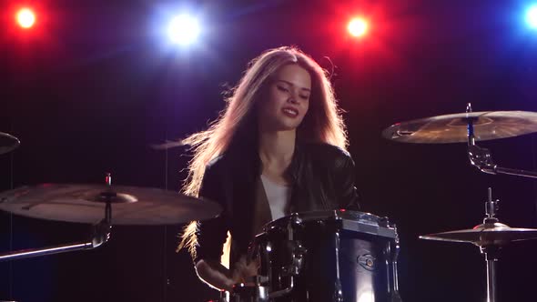 Girl Is Playing the Drums. Black Background. Red Blue Light From Behind