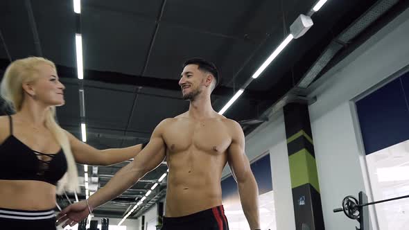 Confident Guy with Nake Torso and Attractive Woman Walking in Gym