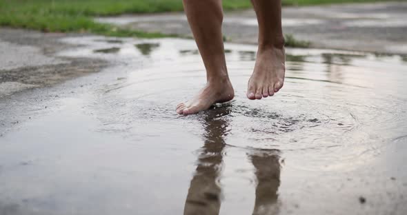 Closeup of feet is splashing water in a puddle