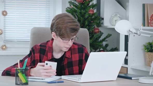 A Teenage Boy Studies Online at Home on a Laptop