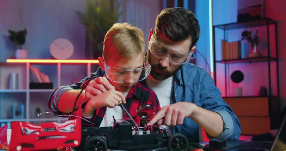 Father in Protective Glasses Teaching to Solder Small Details of Toy Car His Curious Smart Teen Son