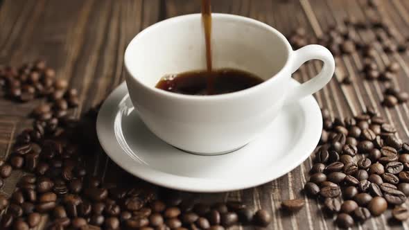 Coffee Cup and Coffee Beans. White Cup of Evaporating Coffee on the Table with Roasted Bean. Slow