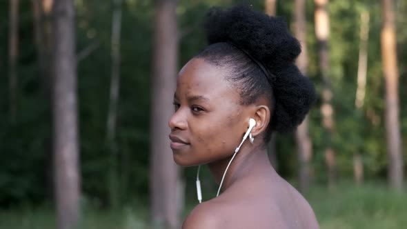 Portrait of a Young African American Woman with Headphones Listening To Music Against the Background