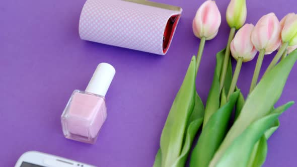 Fresh flower, purse, nail paint and mobile phone on purple background 4k