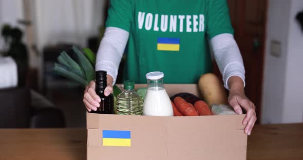 Volunteer preparing food box for ukrainian war refugees - Humanitarian help and aid concept