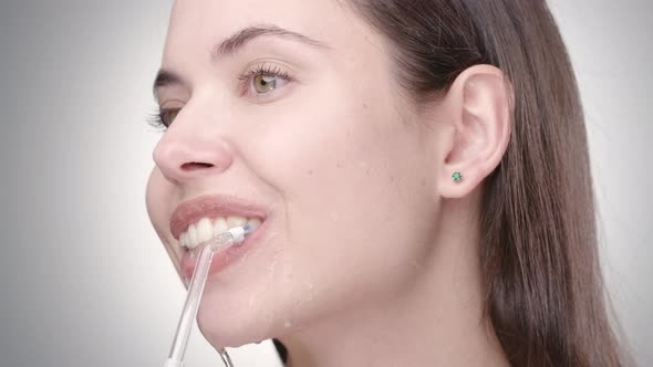 Woman with Nude Makeup Cleaning Teeth with Irrigator 