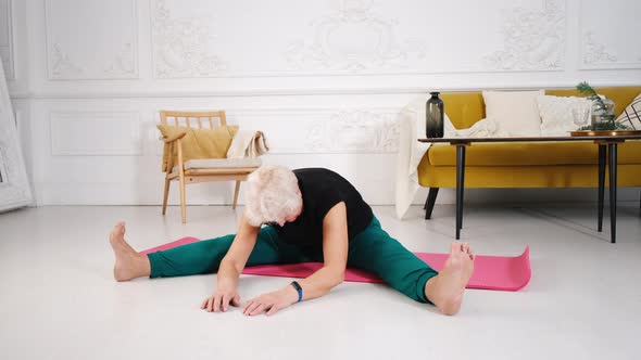 a Beautiful Looking Aged Woman Does Yoga at Home in a Beautiful White Interior