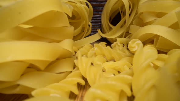 Super Macro Shot of Set Raw Pasta on Wooden Table. Vertical Sliding Forward Over Different Types of