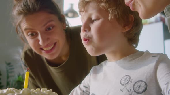 Happy Child Blowing Candle on Birthday Cake at Family Celebration