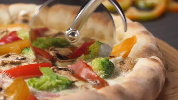 A Pizza Knife Rolls Over the Surface of a Fresh Pizza Cutting It