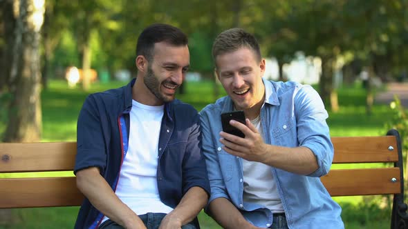 Best Male Friends Looking Through Photos on Smartphone, Having Fun at Park