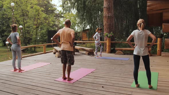 Group of Diversity Sporty in Bodysuit Relax and Stretch By Practicing Yoga with Instructor on Mat