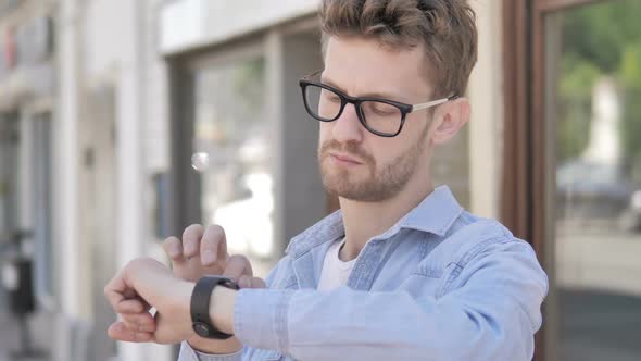 Casual Young Man Using Smartwatch Standing Outdoor