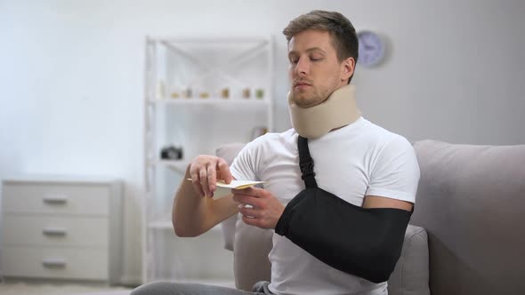 Man in Foam Cervical Collar and Arm Sling Reading Medical Bill, Shocking Price