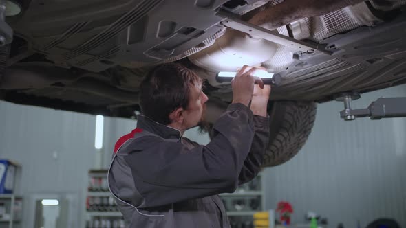 Mechanic Repairs a Car Hanging on a Lift