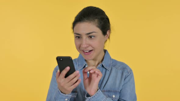 Indian Woman Celebrating on Smartphone, Yellow Background 