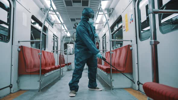 African Man with Protective Suit , Face Shield, Mask and Gloves Disinfecting Interior of the Train. 