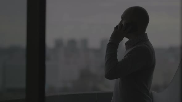 Silhouette of a Man Talking on the Phone Against the Background