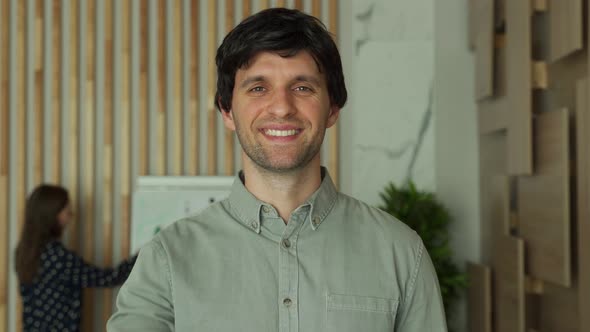 Successful Young Businessman Holding Out His Hand for a Handshake in Office Looks at the Camera