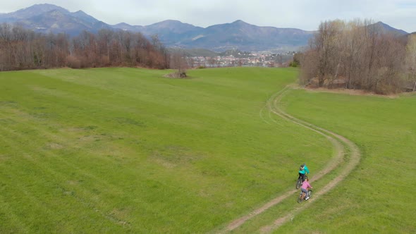 Aerial view: couple cyclist riding mountain bike in the countryside on the Alps