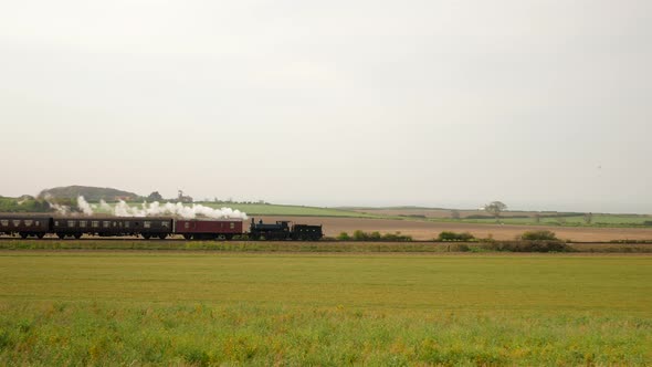 Historic Steam Train with White Smoke Rides in the Countryside